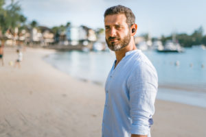 Man standing on the beach wearing Nuheara's IQ buds 2 max