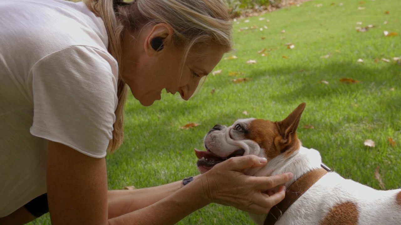 Woman petting dog wearing IQbuds MAX hearing buds